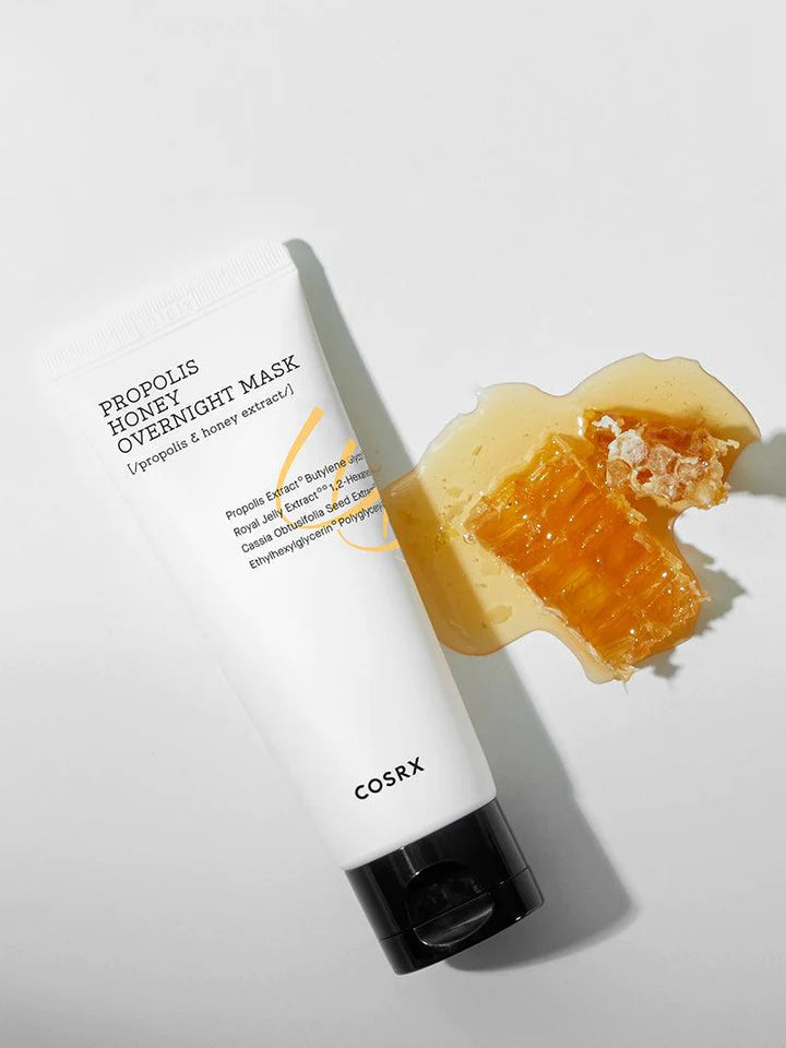 COSRX Full Fit Propolis Honey Overnight Mask på et bord med honning ved siden af 