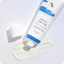 Round Birch Juice Moisturizing Sun Cream på hvid baggrund. En tube med fugtgivende solcreme, der er blevet åbnet, og noget af cremen er presset ud ved siden af tuben. Tuben har en blå og hvid etiket med koreansk skrift og en illustration af en person ved birketræer. SPF 50+ PA++++.